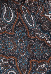 Tumma kangas, jossa on monimutkainen paisley-kuvio sinisen, valkoisen ja ruskean sävyissä. Kankaassa on joustava vyötärö ja sileä pinta.