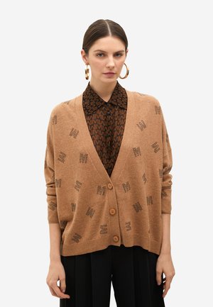 Cárdigan de punto marrón con cierre de botones, que presenta un patrón texturizado de letras estilizadas, usado sobre una camisa oscura con estampado.