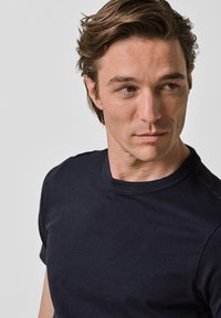 Mörk marinblå t-shirt med kort ärm och rund halsringning, tillverkad av bomull. Slät textur, figursydd design, minimal detaljering.