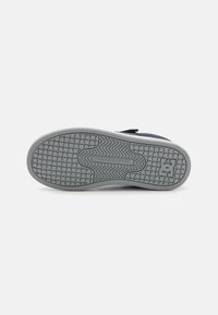 Semelle en caoutchouc grise avec un motif texturé et le logo DC Shoes, présentant un design flexible et un bord renforcé pour la durabilité.