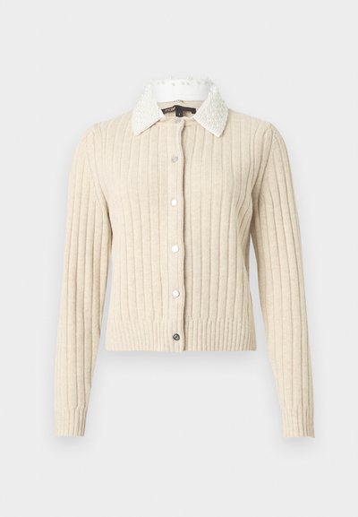 Cardigan beige côtelé à manches longues, col blanc orné de perles, et fermeture boutonnée sur l'avant, sur un fond clair uni.