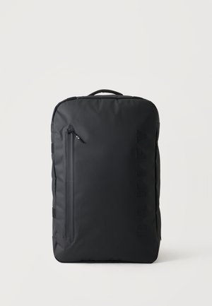 Sac à dos rectangulaire noir avec une poignée supérieure et une poche frontale verticale zippée sur un fond blanc uni.