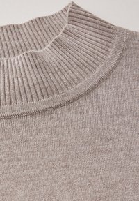 Beige geribde trui met een hoge, omgeslagen hals. Zachte textuur met een soepele breipatroon en subtiele kleurnuances.