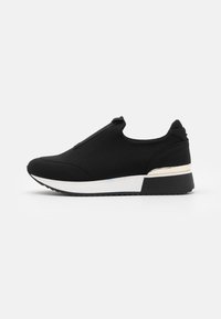 Svart slip-on sneakers i mjukt tyg med en stilren design, vit mellansula med en metallisk accent och texturerad sula för bra grepp.