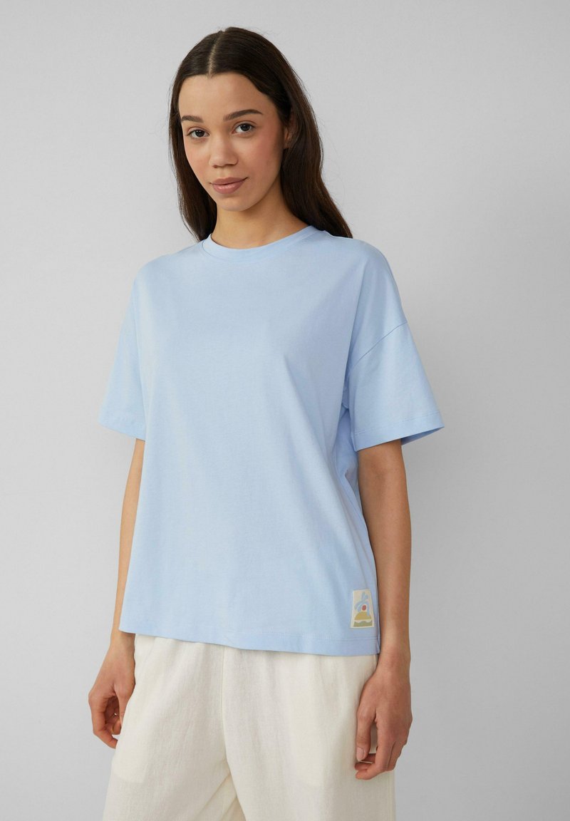 Lichtblauw katoenen t-shirt met korte mouwen, relaxte pasvorm, geribbelde ronde hals en een decoratief label aan de onderkant links.