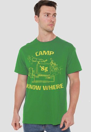 Green cotton T-shirt featuring yellow graphic design of a computer and scientific equipment, text reads "CAMP '85 KNOW WHERE."