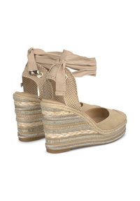 Wedge espadrilles beige con tomaia in tessuto intrecciato, cinturino alla caviglia e suola in juta intrecciata con dettagli metallici e design testurizzato.