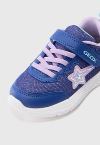 Μωβ και μπλε αθλητικό παπούτσι με γυαλιστερό άνω μέρος από δίχτυ, λαστιχένια σόλα, ροζ κορδόνια σε αντίθεση και διακοσμητικό στοιχείο σε σχήμα αστέρι.