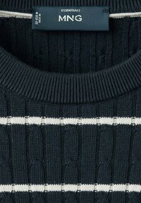 Pull en maille noir avec des rayures horizontales blanches et une étiquette de vêtement portant la mention MNG Essentials en taille moyenne.