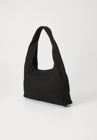 Sort canvas tote bag med et karakteristisk buet håndtag og åben top. Blød tekstur, minimalistisk design, og ingen synlig hardware eller accenter.