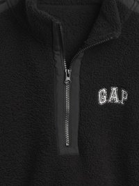 Μαύρο πουλόβερ από φλις με κλείσιμο ζιπ-ζαπ τετάρτου, με υφή επιφάνειας και κεντημένο λογότυπο "GAP" σε λευκό. Λεπτομέρεια μαύρου φερμουάρ.