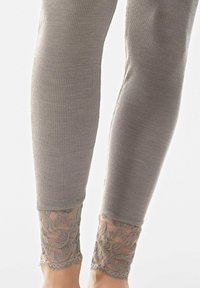 Graue gerippte Leggings mit Spitzenbesatz an den Knöcheln, die mit floralen Mustern verziert sind. Sie sind aus einem weichen Stoff und bieten eine enganliegende Passform.