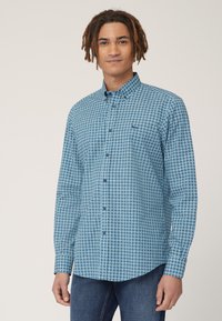 Camicia a pattern blu e bianco con colletto button-down, maniche lunghe e orlo curvo. Presenta una tasca sul petto. Il tessuto appare liscio.