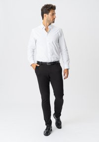 Hvid skjorte med knapper, sorte tætsiddende bukser, sort bælte og skinnende sorte sko. Casual look med en glat tekstur og skræddersyet design.