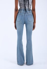 High-waisted, light blue denim flared jeans with two back pockets and stitching detail, featuring a classic five-pocket design.