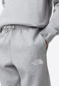 Grå bomullssweatpants med elastisk midjebånd og snor, med sidelommer og en hvit logo på venstre ben.