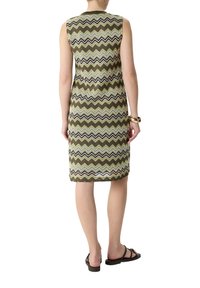 Sukienka bez rękawów do kolan z wzorem w zygzaki w kolorze zielonym, czarnym i białym. Wykonana z teksturowanej tkaniny, w zestawie z płaskimi sandałami.