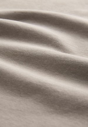 Țesătură de bumbac bej deschis care prezintă o textură moale și netedă, cu o ușoară elasticitate și un aspect ușor încrețit, evidențiind profunzimea și finețea.