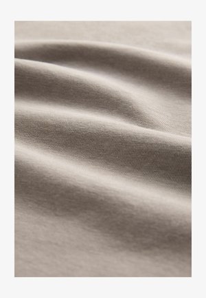 Tela de algodón de color beige claro que muestra una textura suave y lisa con un ligero estiramiento y una apariencia ligeramente arrugada, enfatizando la profundidad y la suavidad.