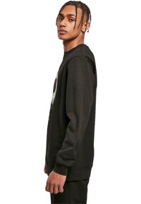 Black sweatshirt made from cotton, featuring a crew neck, long sleeves, and a graphic print on the front with contrasting colors.