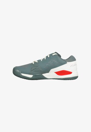 Zapatilla deportiva gris con parte superior de malla, puntera reforzada y suela de goma. Presenta detalles en rojo y blanco, patrones texturizados y cuello acolchado.
