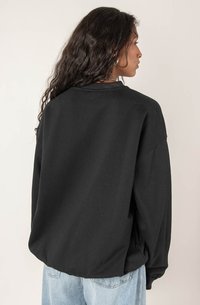 Czarny oversize sweatshirt z prążkowanym kołnierzem, obniżonymi ramionami i miękką fakturą. Posiada gładki tył i luźny krój.