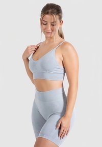 Vaaleansinisestä aktiivivaatteiden setistä löytyy istuva toppi, jossa on ohuet olkaimet, sekä korkeavyötäröiset shortsit pehmeästä, teksturoidusta kankaasta.