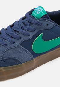 Blå mocka och tyg sneakers med grön Nike swoosh, texturerade snören och transparent gummisula. Har en vadderad krage och logotag.