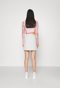 Pitkähihainen, muotoiltu paita vaaleanpunaisessa ja oranssissa sitruunatunnelmassa, yhdistetty valkoiseen denimmihameeseen. Valkeat tennarit viimeistelevät asukokonaisuuden.