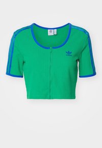 Zelený zkrácený zipový top vyrobený z žebrované látky, se modrými akcenty na rukávech a kulatým výstřihem, s malým logem na hrudi.