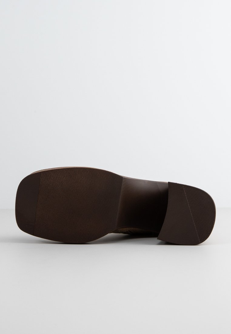 Semelle de chaussure marron avec un design plat, texture striée et un léger talon. Fabriquée à partir d'un matériau durable, avec une finition lisse et des détails minimalistes.