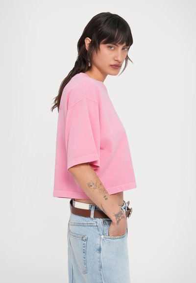 Ροζ κοντομάνικο cropped t-shirt από μαλακό βαμβάκι. Διαθέτει άνετη εφαρμογή και ευθεία τελείωμα. Συνδυάζεται με ψηλόμεσα τζιν σορτς.