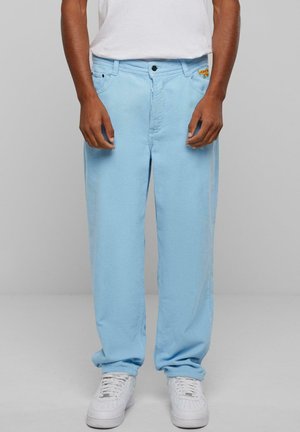 Light blue corduroy pants with a straight leg design, front pockets, and a small logo on the waistband, paired with white sneakers.