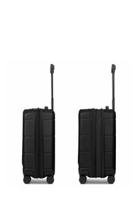 Schwarzer Hartschalen-Kabinenkoffer mit strukturierter Oberfläche, vertikalen Rillen, Doppelrollen und ausziehbarem Griff. Sichtbarer Reißverschluss.