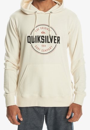 Sweat à capuche Quiksilver beige avec poche avant, cordons, et logo circulaire noir-rouge indiquant "The Original Quiksilver Surf Company 1969".