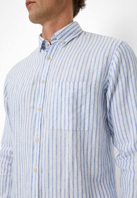 Lichtgewicht, witte linnen shirt met verticale blauwe strepen, button-down kraag en zakje op de linkerkant van de borst. Zachte textuur en casual pasvorm.