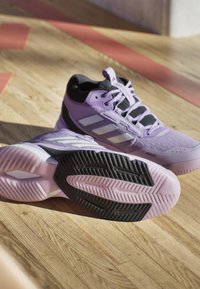 Light purple athletic shoes with black accents, textured upper, white stripes, and a black rubber sole featuring a patterned tread design.