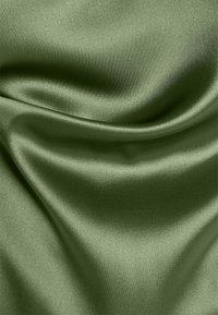 Tissu satin vert avec une texture lisse et brillante et un tissage fin, présentant un drapé doux et de légers plis sur la surface.