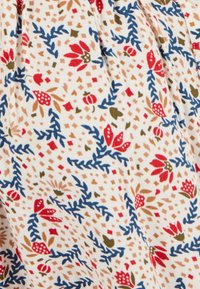 Tessuto di cotone con sfondo bianco, decorato da un motivo floreale in rosso, blu e verde, con piccole forme geometriche sparse.