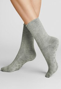 Graue, knielange Socken mit geripptem Material, weichem Stoff und dekorativem Wellenrand; gepunktetes, rutschfestes Muster auf den Sohlen.