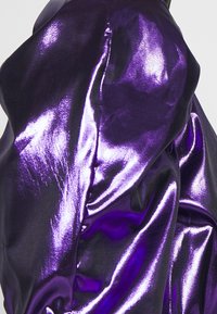 Tissu en satin violet avec un éclat brillant, présentant une texture lisse et drapée avec des plis subtils, mettant en valeur un design élégant et moderne.