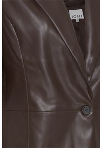 Blazer en cuir marron avec une texture lisse, des revers crantés et un détail de bouton noir unique à l'avant. Étiquette de marque visible à l'intérieur.