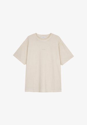 Beżowa bawełniana koszulka z krótkim rękawem, o okrągłym dekolcie i małym napisem "OH APRIL" na środku klatki piersiowej.