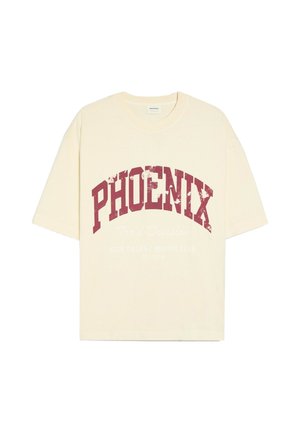 Personne portant un t-shirt blanc Phoenix et un jean foncé, en équilibre sur le bord d'une piscine ronde dans un jardin avec des arbres et des buissons.