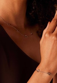 Sierra zilveren sieraden met hartvormige accenten aan een delicate ketting. De armband en ketting hebben een gepolijste afwerking en een verfijnd ontwerp.