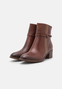 Bottines en cuir marron avec un panneau texturé, détail de sangle tressée et un talon carré de 5 cm. Finition lisse, design à bout rond.