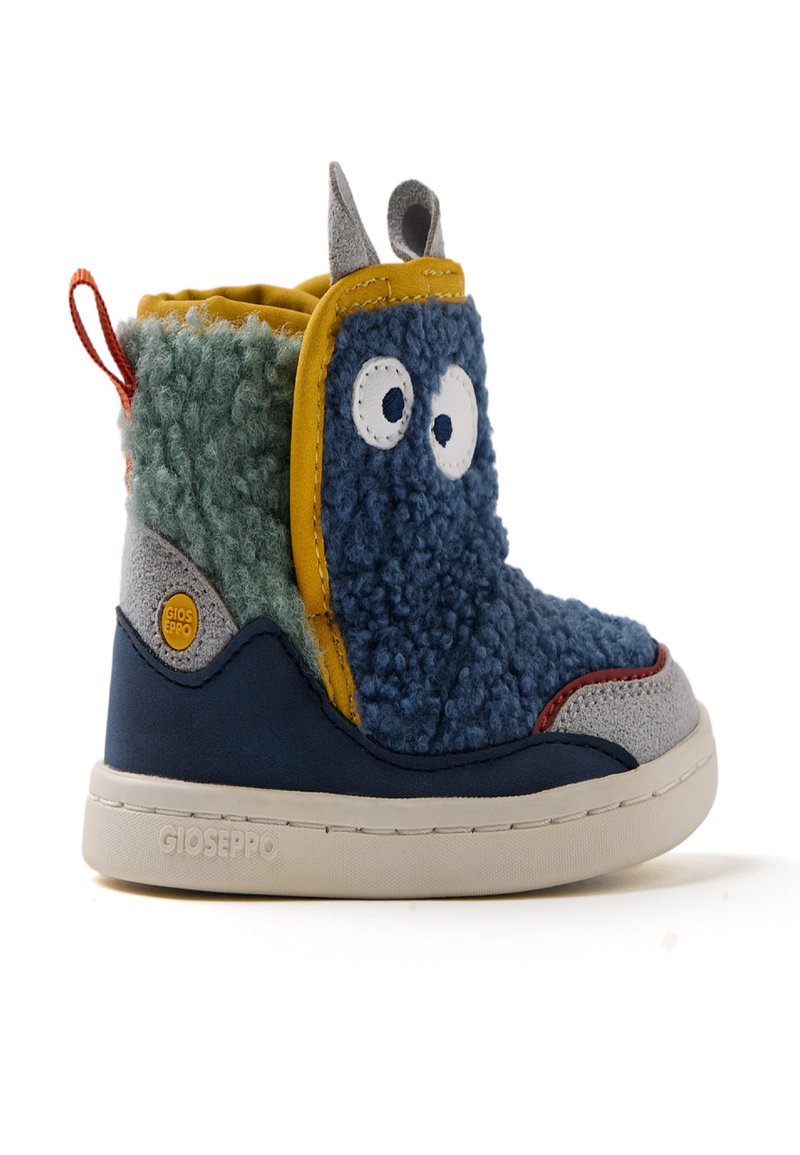 Botas infantiles coloridas hechas de materiales multi-texturizados. Presentan secciones en azul, verde y gris, con detalles de ojos y orejas juguetonas.
