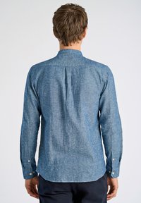 Camicia in chambray blu con maniche lunghe, colletto a punta, piega sul retro e polsini con bottone. Tessuto testurizzato con un sottile motivo mélange.
