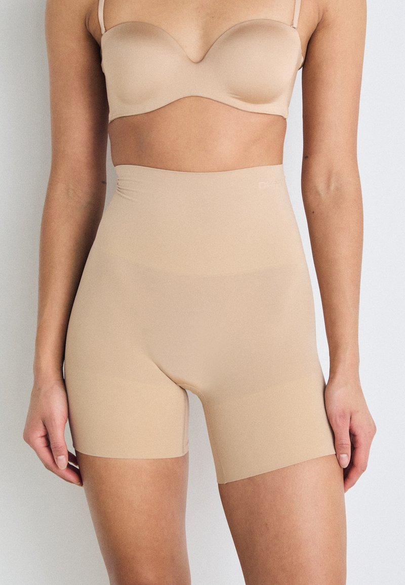 Shorts bej cu talie înaltă, confecționați dintr-un material neted și elastic, având un design fără cusături și o potrivire confortabilă în jurul taliei și coapselor.