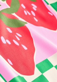 Färggafabrik med stora röda jordgubbar och gröna blad på en rosa och grön rutigt bakgrund. Slät textur med livfullt tryck.
